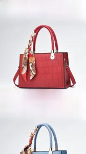 Detail of crocodile embossed leather tote with silk scarf handle in wine red finish