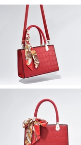 Detail of red crocodile textured handbag featuring a woven handle and silk scarf decor
