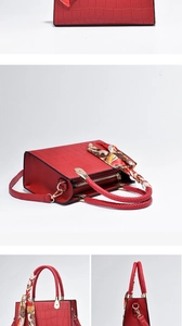 Detail of red crocodile pattern handbag featuring a woven handle and silk scarf