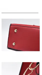 Detail of red croc-embossed leather bag showing bottom gold rivets and D-ring hardware