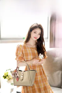 Détail d'un sac à main beige en cuir grainé avec foulard en soie et fermoir rotatif chic