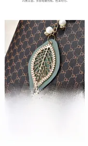 Dettaglio della borsa monogramma marrone con ciondolo a foglia d'oro e perle