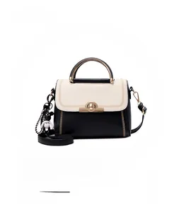 Detail of color-block handbag with V-shaped stitching, metal handle and bear charm