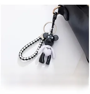Close-up of black and white bear charm with braided lanyard on leather bag detail