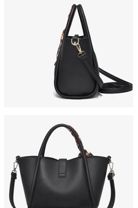 Détail d'un sac à main noir en cuir litchi avec foulard en soie et finitions dorées
