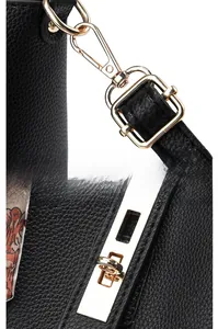 Détail du fermoir en métal doré et du verrou pivotant sur un sac en cuir grainé noir