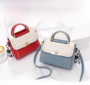 Detail of color-block handbags with V-shaped stitching and bear charm on bright background
