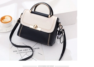 Detail of contrast handbag with gold ring handle and bear charm in a lifestyle setting