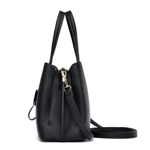 Minimalist black lychee texture handbag with gold hardware and shoulder strap in side view