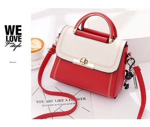 Detail of red and white leather crossbody bag with stitching and gold twist lock