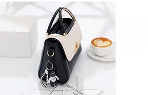 Detail of a chic monochrome handbag with a gold metal handle and a cute bear charm