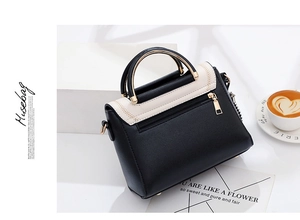Detail of minimalist black and white leather handbag with golden circular handle