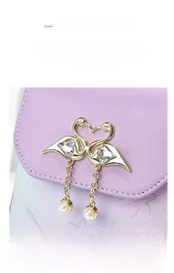 Detail of light purple bag featuring golden swan hardware with crystals and pearls