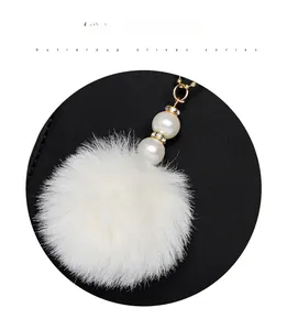 Detail eines weißen Pelz-Anhängers mit Perlen und goldener Metallkette für Taschen