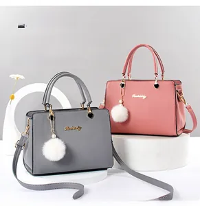 Detailansicht der grauen und rosa PU-Lederhandtaschen mit Herzverschluss und Fellanhänger