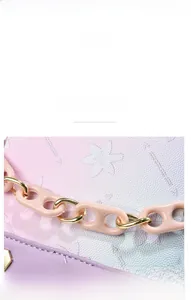 Detail view of pink gradient leather handbag with embossed floral patterns and acrylic chain