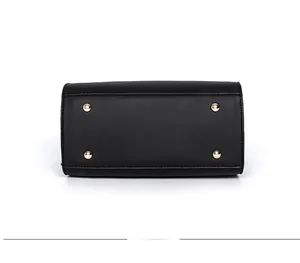 Detailsicht des schwarzen Lederhandtaschen-Bodens mit goldenen Schutznieten und Nähten