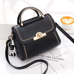 Black leather handbag with gold embroidery, metal handle, and teddy bear charm accessory