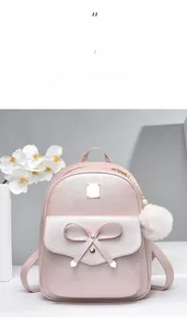 Detailed view of pink Saffiano leather backpack with bow accent and white pom-pom charm