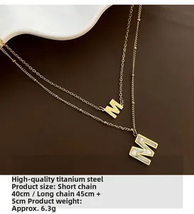 Détail du collier double en titane avec pendentif lettre M et incrustation nacre