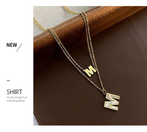 Détail du collier double rang en acier titane doré avec pendentif lettre M en nacre