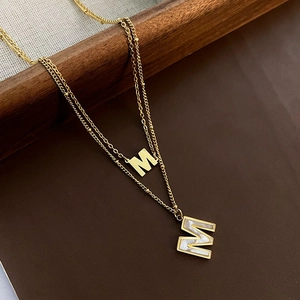 Collier double rang en acier titane doré avec pendentifs M et incrustation nacre