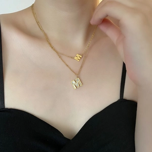 Collier double épaisseur en acier titane doré avec lettre M et pendentifs nacre