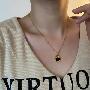Gold stainless steel necklace featuring a double-sided black heart pendant and small beads
