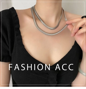 Detailed close-up of double-layered silver flat snake chain necklace on black fabric
