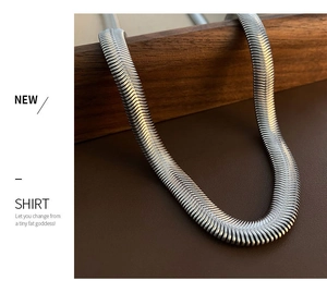 Close-up of a wide silver flat snake chain necklace with high-gloss metallic texture
