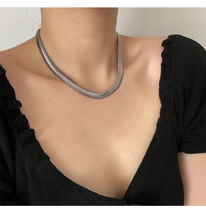 Close-up of flat silver snake chain necklace on model showcasing the smooth woven metal texture
