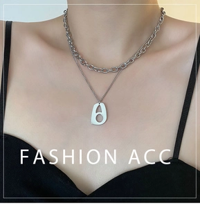 Detail of layered silver chain necklace with geometric cutout pendant on a model