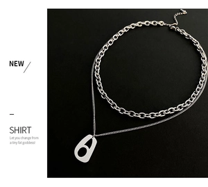 Detail of silver double-layered necklace featuring Cuban chain and geometric pendant