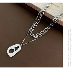 Detail view of double-layer geometric necklace with polished steel chain and hollow pendant