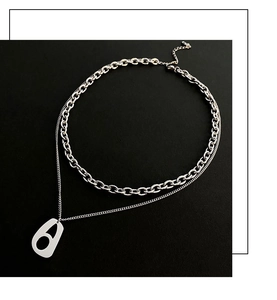 Close-up of double layer silver cuban chain with an oval hollow pendant on black background