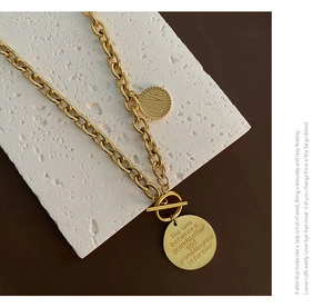 Macro detail of gold OT clasp chunky chain with engraved round letter pendants