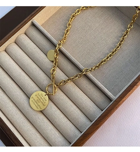 Detail of T-bar gold necklace with double round pendants showing engraved love quote
