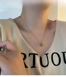 Gros plan d'un collier pendentif pomme dorée sur un mannequin avec bague assortie