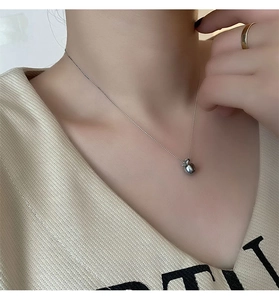 Gros plan d'un collier avec pendentif pomme minimaliste porté sur la clavicule