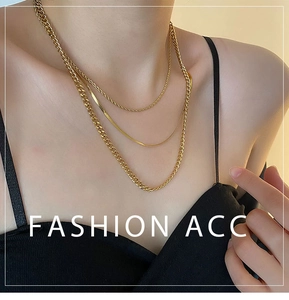 Detailed view of triple-layered golden necklace featuring snake, twist, and NK chain styles