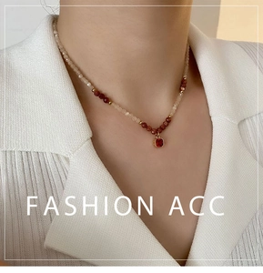 Close-up of a necklace with a ruby-red square pendant and natural stone beaded chain