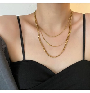 Detail of three-layer layered gold necklaces featuring rope, snake, and Cuban link chains