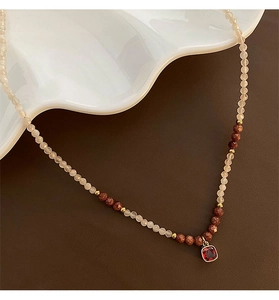 Detailed shot of moonstone beads with square red gemstone pendant on a white plate