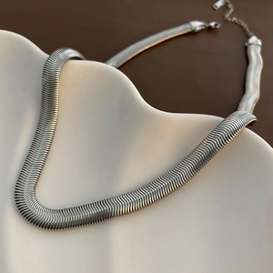 Elegant silver flat snake chain necklace with lobster clasp on a white wavy tray