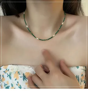 Detail of vintage necklace with malachite green stones and freshwater pearls worn by model