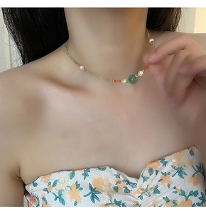 Detail of freshwater pearl necklace with green zircon pendant and vintage colorful beads