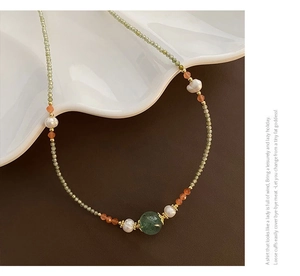 Detail of dark green beaded necklace with natural freshwater pearl and gold spacer beads