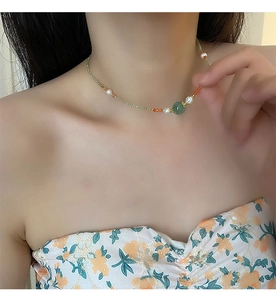 Detail of beaded necklace with light green zircon and freshwater pearl on neck