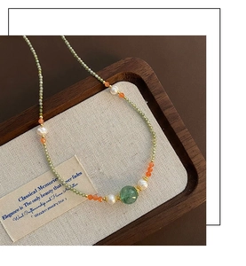 Macro detail of freshwater pearls and green zircon beads on a vintage gold chain
