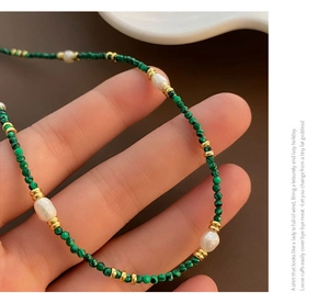 Macro shot of malachite green beads and freshwater pearl necklace with gold spacers
